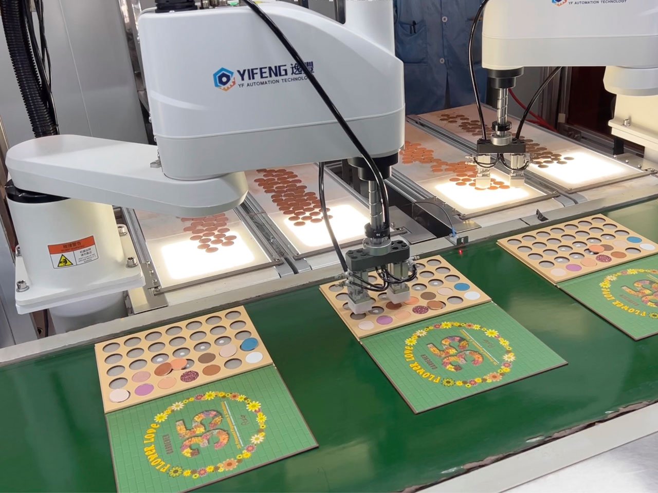 A robotic arm is assembling eyeshadow palettes.